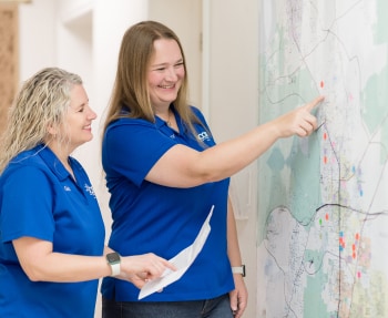 Jacob Heating & Air Conditioning staff smiling while observing large map on the wall