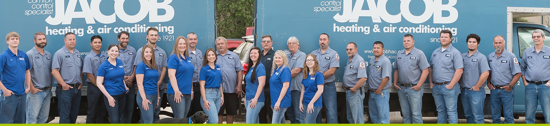Full Jacob Heating & Air Conditioning team standing together in front of two large blue company trucks