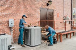 Two service technicians working on a commercial air conditioning unit.