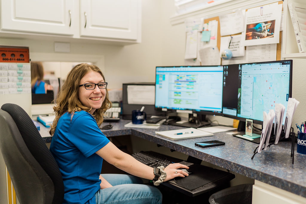 Jacob HAC employee sitting in office smiling in front of computer