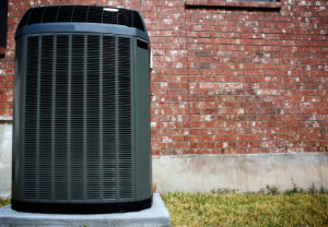 A black HVAC unit outside a brick home.