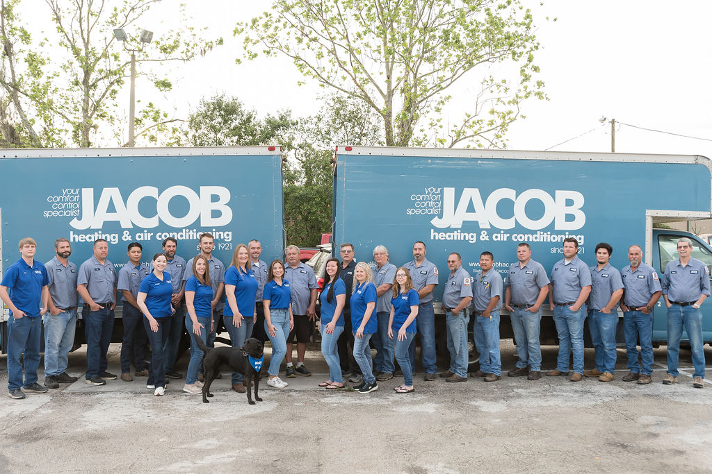 Jacob Heating & Air Conditioning employees standing in front of two work trucks