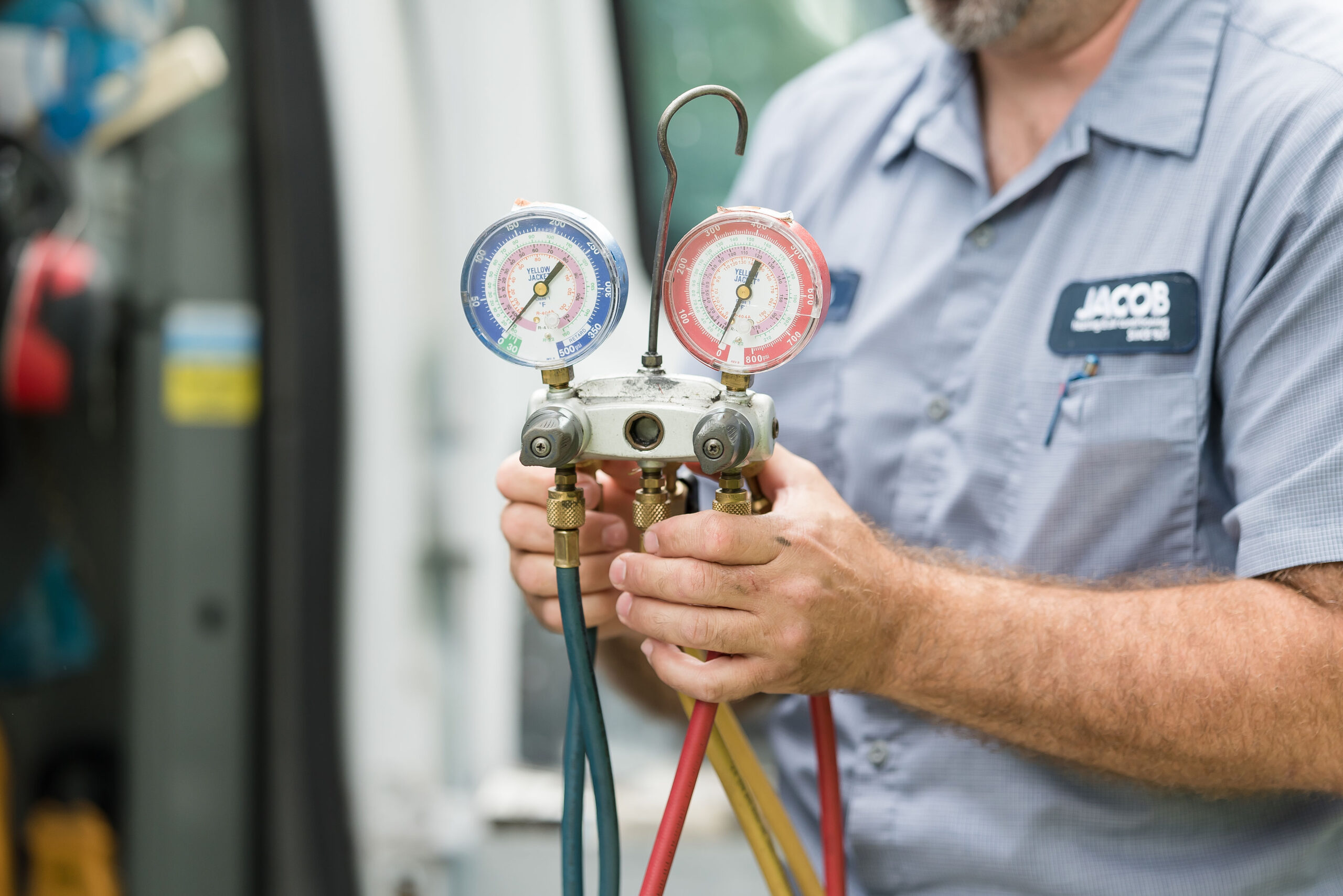 A service technician holding a yellow jacket manifold gauge.