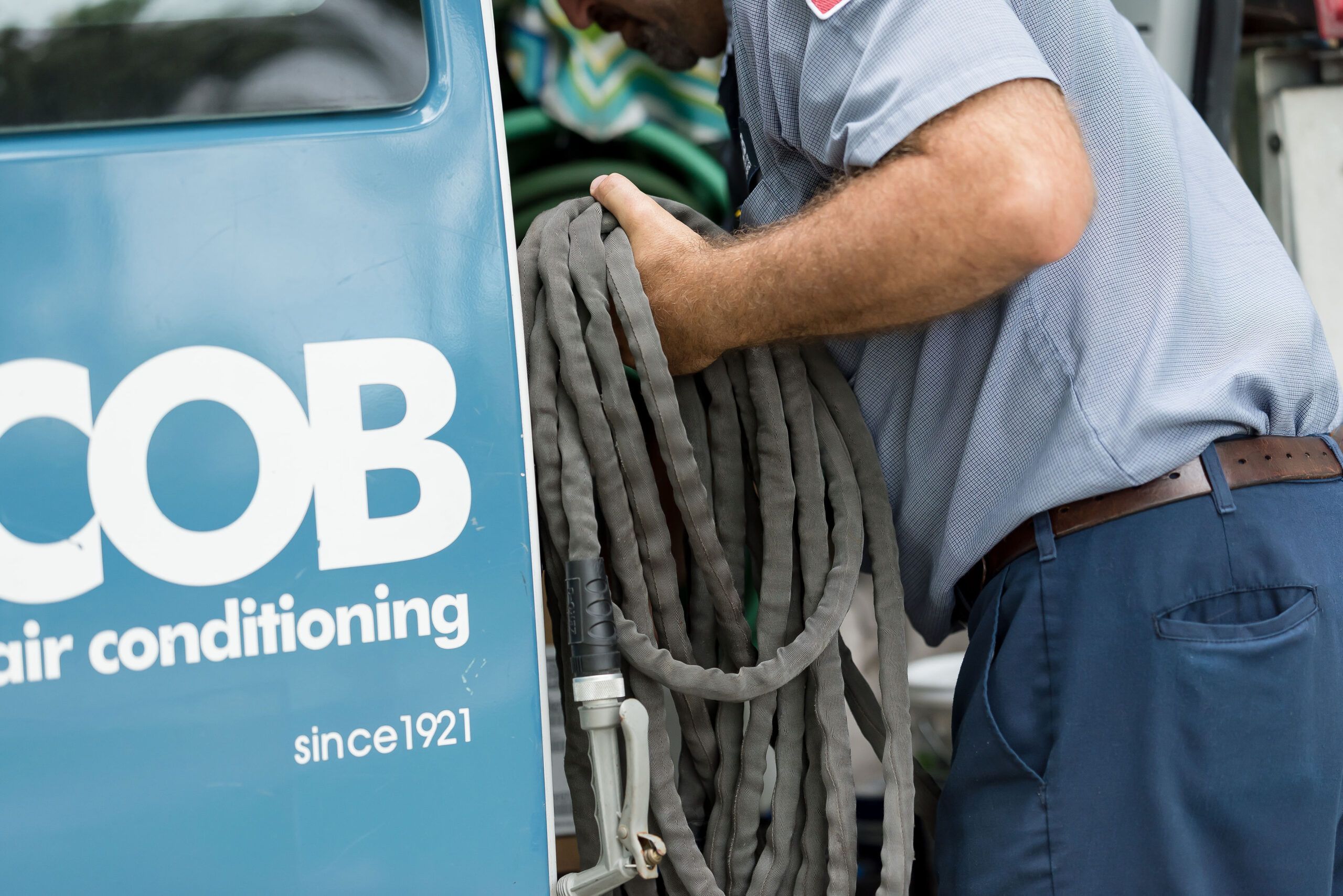 A service technician putting a garden hose in the Jacob Heating & Air van
