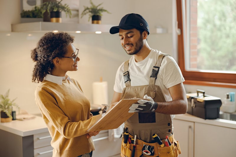 A interaction between a homeowner and a service technician in a kitchen.